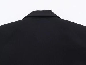 Detail view showing the neckline and woven fabric texture on the back of the black dress
