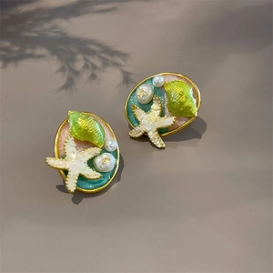 Close-up of enamel dolphin starfish earrings with gold plating and pearl details