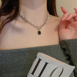 Close-up of a silver-toned chunky chain necklace featuring a rectangular black pendant