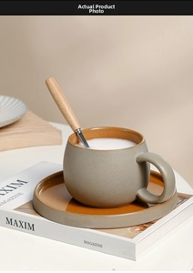 Dettaglio della tazza da caffè in ceramica grigio opaco con interno ambrato e cucchiaio in legno