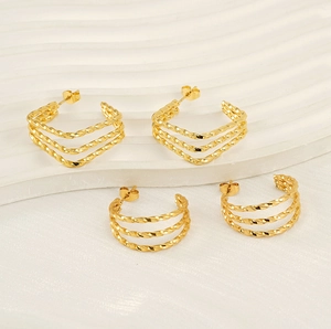 Detailed macro of golden geometric multilayer twisted hoop earrings in square and round shapes