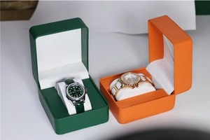 Detailweergave van quartzhorloges in luxe bosgroene en oranje lederen geschenkdozen