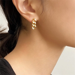 Close-up of gold-plated stainless steel punk Cuban chain earrings worn on ear