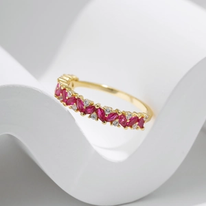 Elegant gold ring with marquise red gemstone and small diamonds on a white base