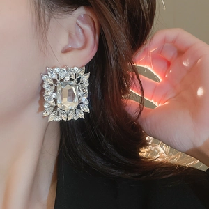 Detailed view of silver rectangular stud earring with sparkling zircon clusters on ear