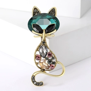 Macro shot of gold cat brooch showing emerald crystal head and hollow body details