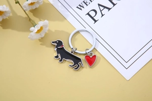 Detail of dachshund enamel keychain with red heart charm on yellow background