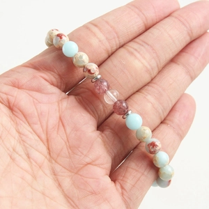 Handheld view of natural stone beaded bracelet with blue and reddish brown mineral stones