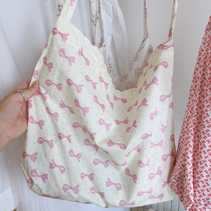 Détail du sac cabas en coton avec motifs de nœuds roses et petits pois bleus doux