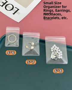 Three sizes of clear PVC jewelry storage pouches organized in a dark green tray