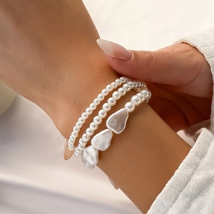 Detailed close-up of a three-piece layered pearl bracelet set with heart-shaped accents