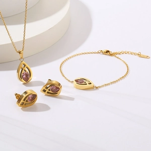 Three-piece gold jewelry set with pink teardrop gems including necklace, bracelet, and earrings