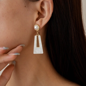 Elegant gold-plated square cutout pearl earring worn by model in a soft lighting close-up