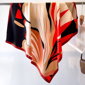 Detail of silk-like scarf featuring abstract floral prints and red rolled edge stitching