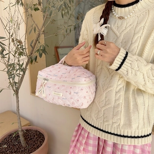 Detailed macro view of pink quilted makeup bag with bow prints and sturdy top handle