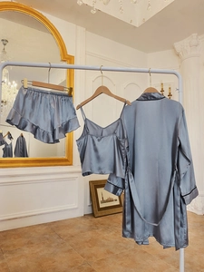Three-piece silver-blue satin pajama set with robe, V-neck top and ruffled shorts hanging