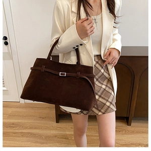 Detail shot of brown faux suede tote bag with decorative straps and metal buckles