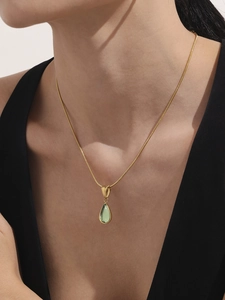 Détail d'un pendentif goutte de pierre vert clair sur une chaîne serpent dorée femme