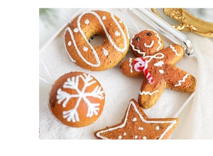 Close-up of gingerbread man and snowflake foam ornaments on white snow background