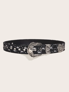 Detail of vintage black denim belt with distressed holes, studs and carved silver buckle