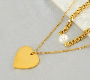 Macro shot of gold heart pendant and pearl on double layered chain necklace