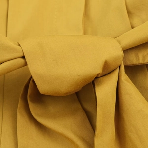 Détail de la robe midi en popeline jaune moutarde avec nœud élégant à la taille et texture
