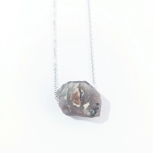 Macro detail of raw purple crystal stone pendant with natural texture on silver chain
