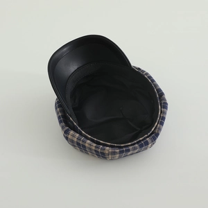 Close-up of checkered newsboy cap showing blue khaki fabric and black leather brim