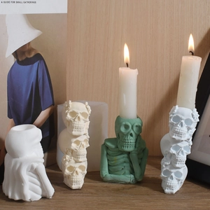 Detailed view of skull-shaped candle holders and a green thinker skeleton statue