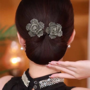 Vue détaillée de pinces à cheveux fleurs élégantes avec strass sombres sur un chignon