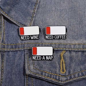 Enamel battery status pins set with 'NEED WINE', 'COFFEE' and 'NAP' text on denim jacket