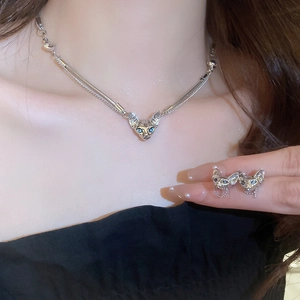 Silver cat-shaped necklace and earring set with blue cat-eye stones on a model