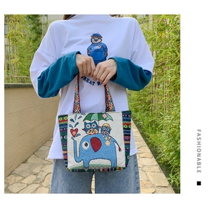Detailed embroidery on canvas tote bag with elephant and owl illustration in outdoor setting