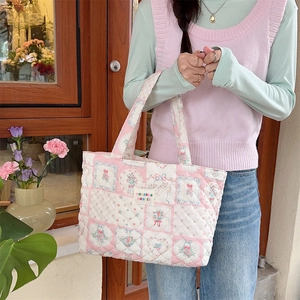 Close-up of pink floral quilted tote bag with vintage flower patterns and logo label