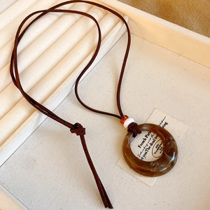 Close-up of vintage irregular circle pendant necklace with brown cord and resin marble texture