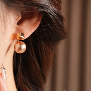 Detailed macro view of vintage gold pearl earrings with faceted amber crystal detail
