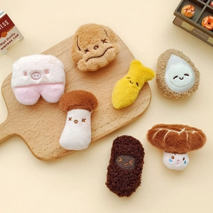 Collection of cute cartoon plush brooches including avocado and mushroom on wooden tray