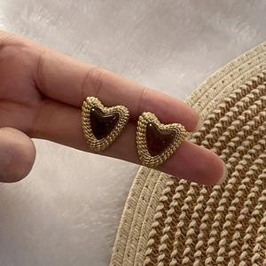 Close-up of vintage heart stud earrings featuring golden woven texture and amber resin