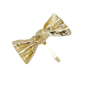 Minimalist golden metal bow hair clip with textured surface for low ponytail styles
