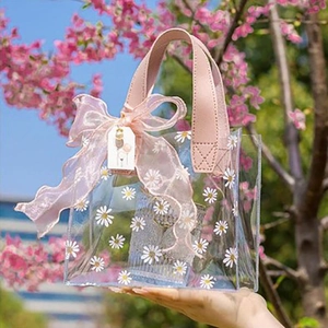 Close-up of a floral PVC gift bag with pink bow and handle against a cherry blossom background