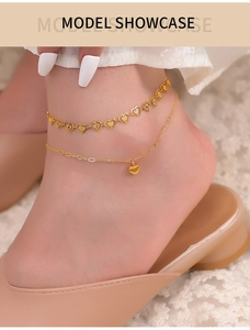 Detail of elegant gold double-layered heart anklet with heart pendant worn on model