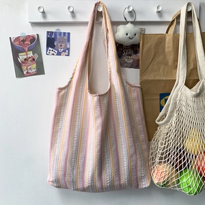 Détail du sac cabas en seersucker texturé rose et jaune suspendu à un crochet blanc