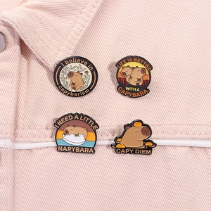 Detail of four cute Capybara enamel pins styled on pink denim fabric with pun text