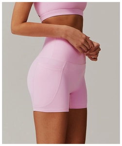 Detail of high-waisted pink yoga shorts featuring hidden side pockets and elastic fabric