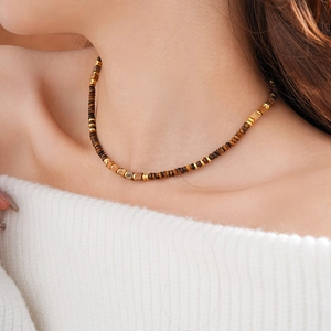 Close-up of square tiger eye beaded necklace with brown and gold accents on a model