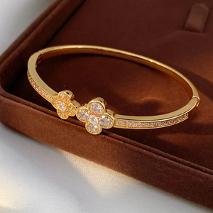 Gold-plated clover bangle featuring sparkling white zircon pave set on a luxury velvet case