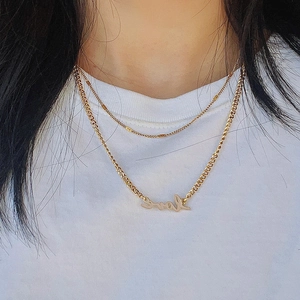 Detail of layered gold titanium necklace featuring a fine chain and Love pendant
