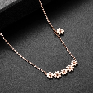 Detailed view of 18k gold daisy flower necklace on textured black leather surface