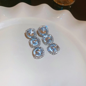 Detailed macro view of square light blue crystal earrings with sparkling silver diamond halo