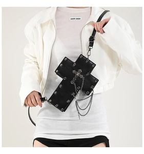 Detail of gothic cross-shaped handbag with silver studs and multilayer metal chains